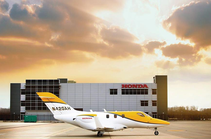 Image d’un HondaJet jaune devant un bâtiment Honda.